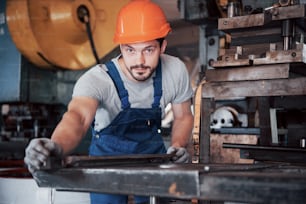 Portrait of a young worker in a hard hat at a large waste recycling factory. The engineer monitors the work of machines and other equipment.