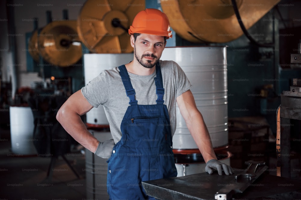 Ritratto di un giovane operaio in un elmetto in una grande fabbrica di riciclaggio dei rifiuti. L'ingegnere monitora il lavoro delle macchine e di altre apparecchiature.
