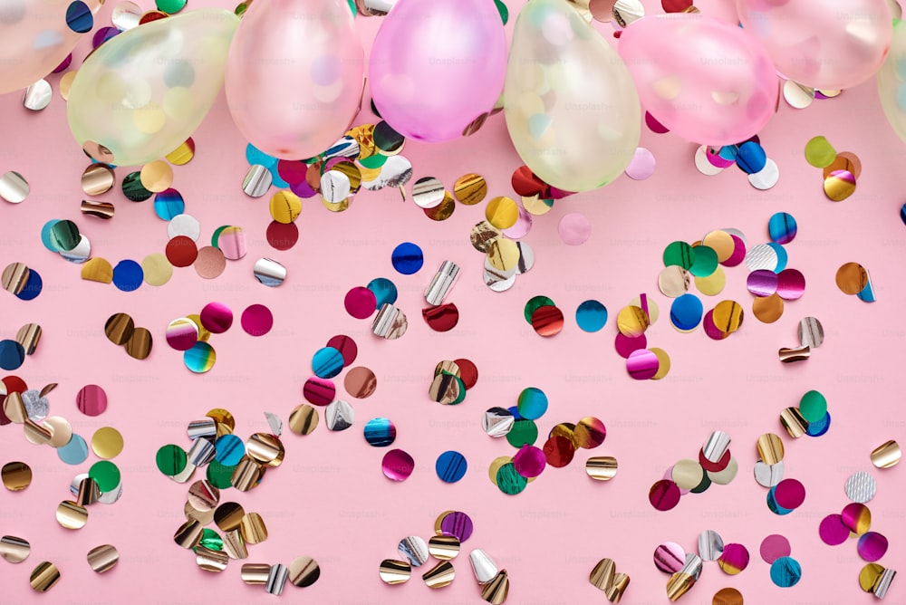 La migliore festa di compleanno Palloncini colorati e coriandoli per il compleanno su sfondo rosa. Vista dall'alto