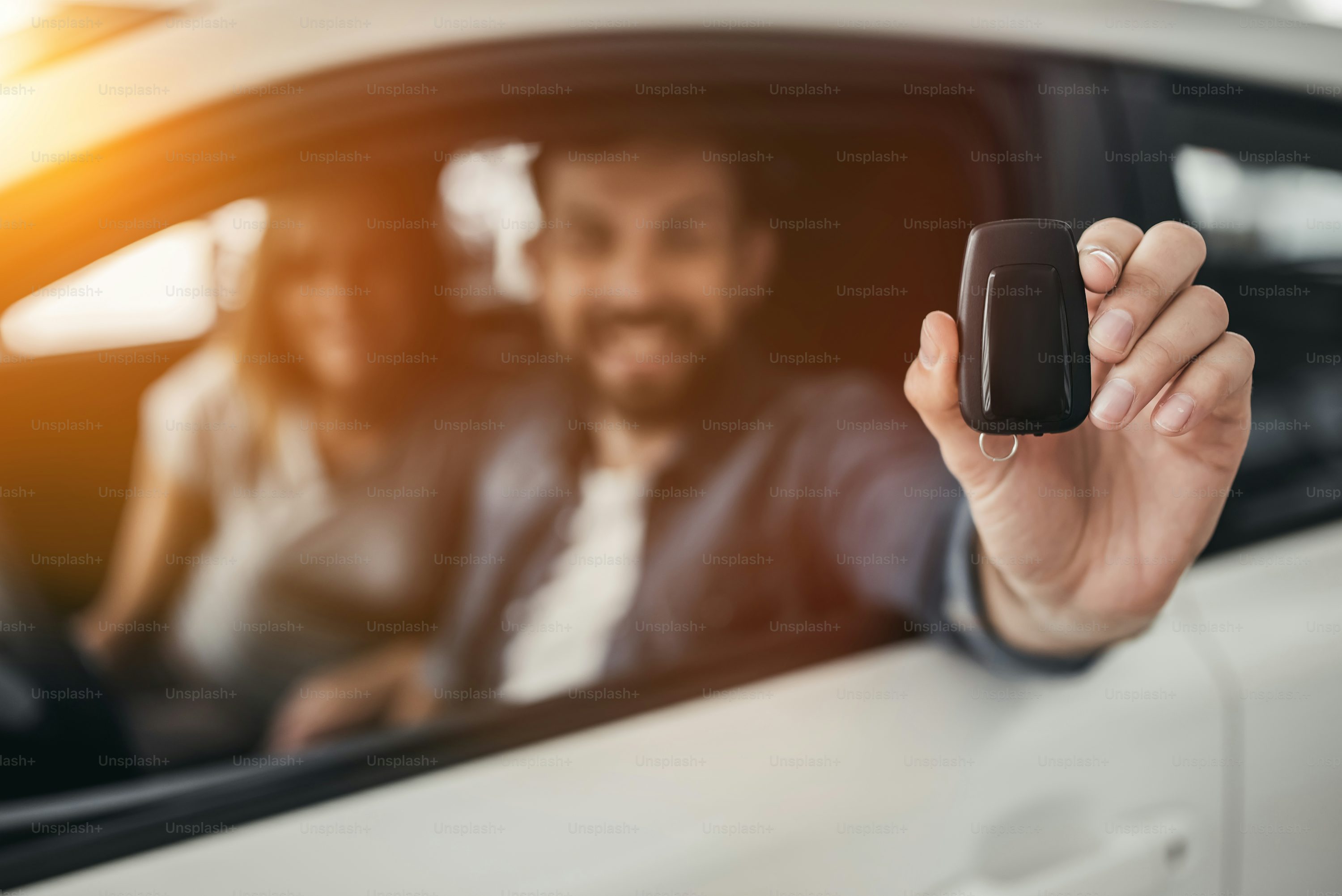Happy beautiful couple is choosing a new car at dealership.