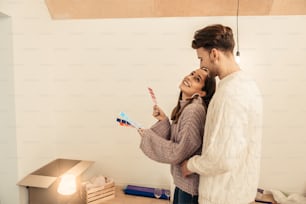 Man hugging. Bearded man coming and hugging his wife choosing colors for their bedroom