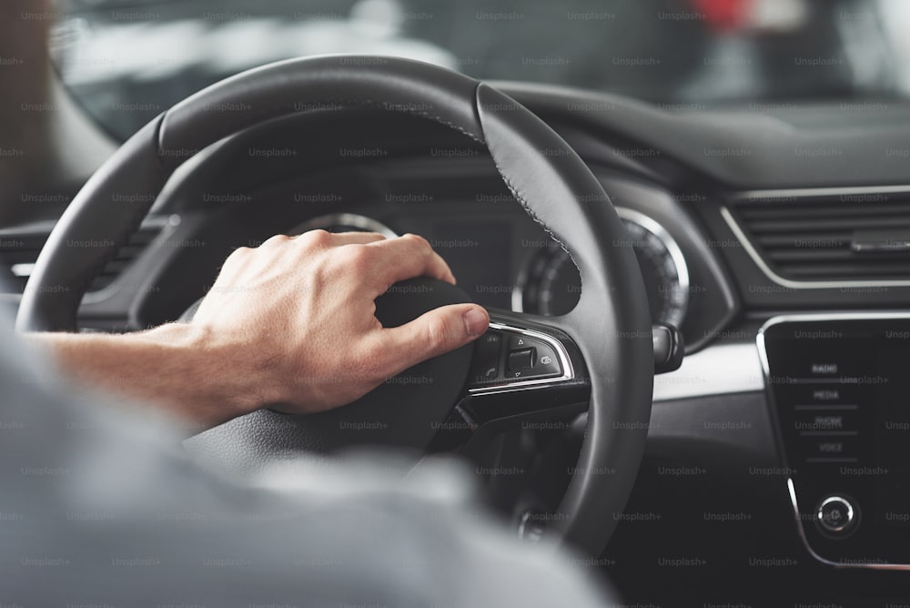 Las grandes manos de un hombre en un volante mientras conduce un automóvil