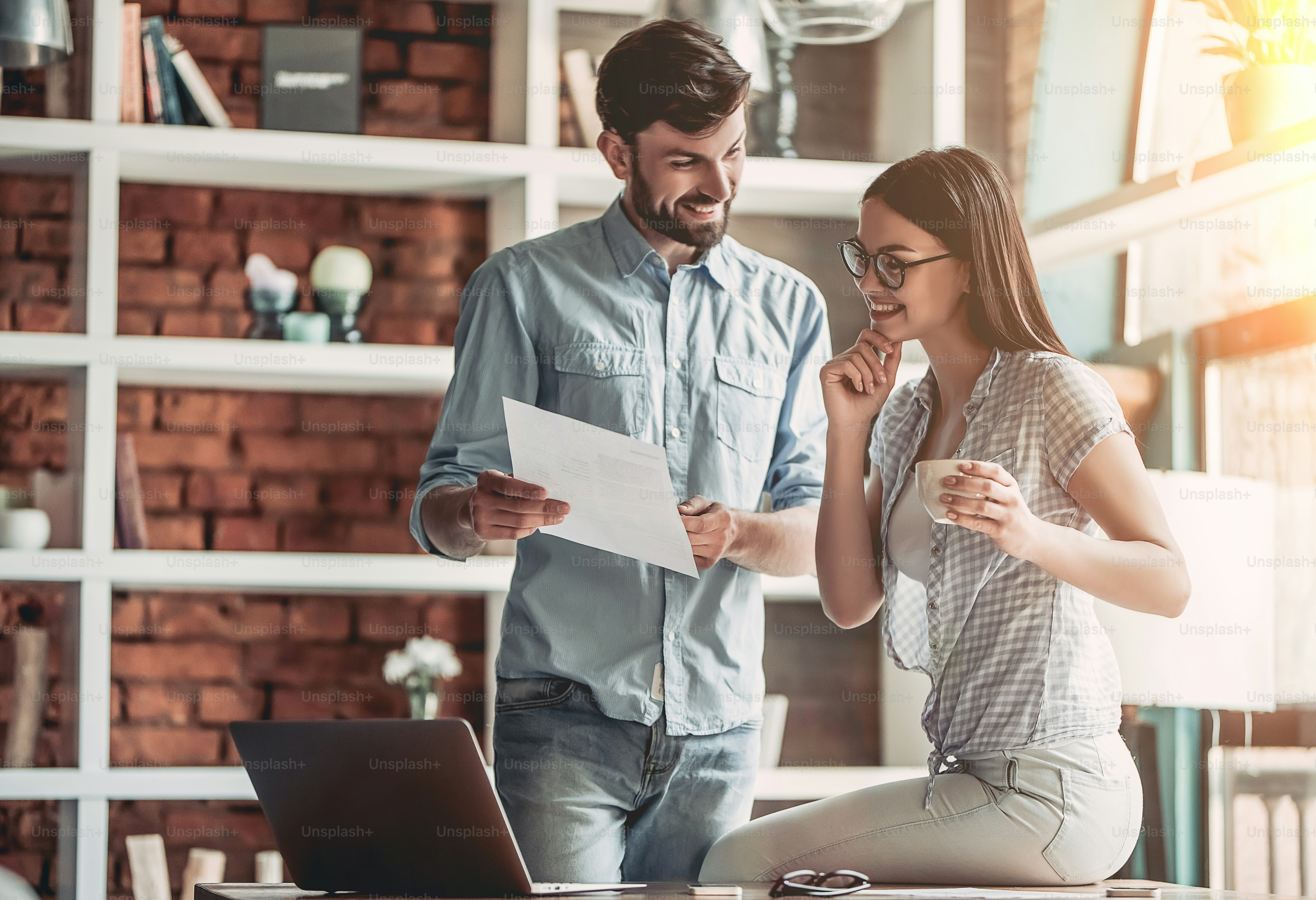 Young couple is working in cafe. Discussing the latest news and smiling.