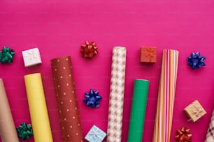 Dress up your gift with bright and beautiful gift wrapping paper. Rolls of bright wrapping paper on pink background.