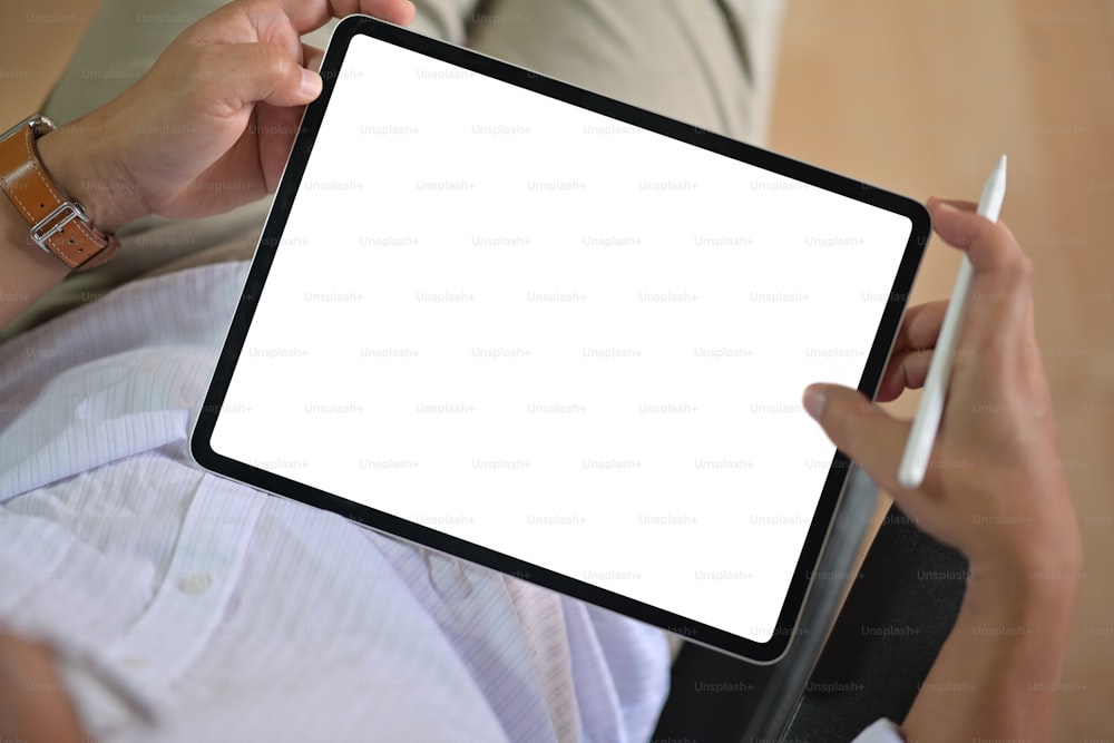 Primer plano de las manos masculinas sosteniendo la tableta de dibujo moderna de la pantalla en blanco