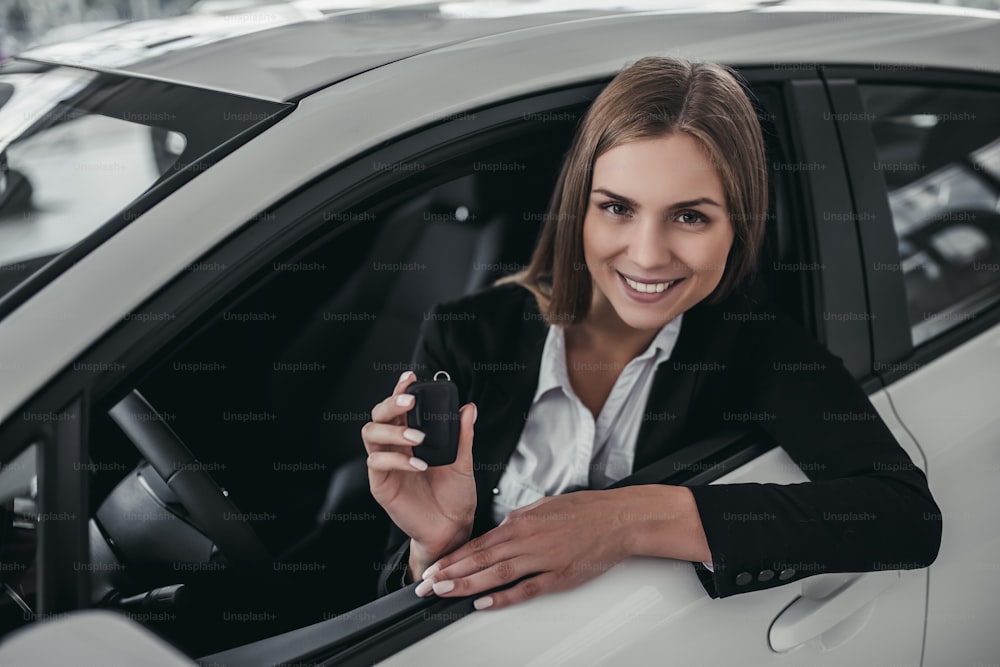 Attractive young businesswoman is choosing new vehicle in car dealership.