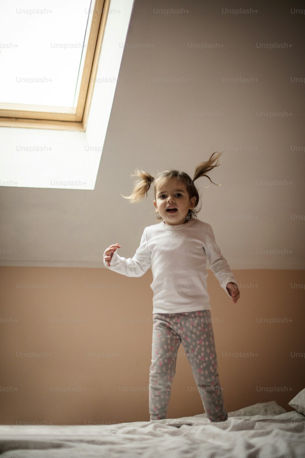 Bouncing for joy. Little girl jumping on bed.