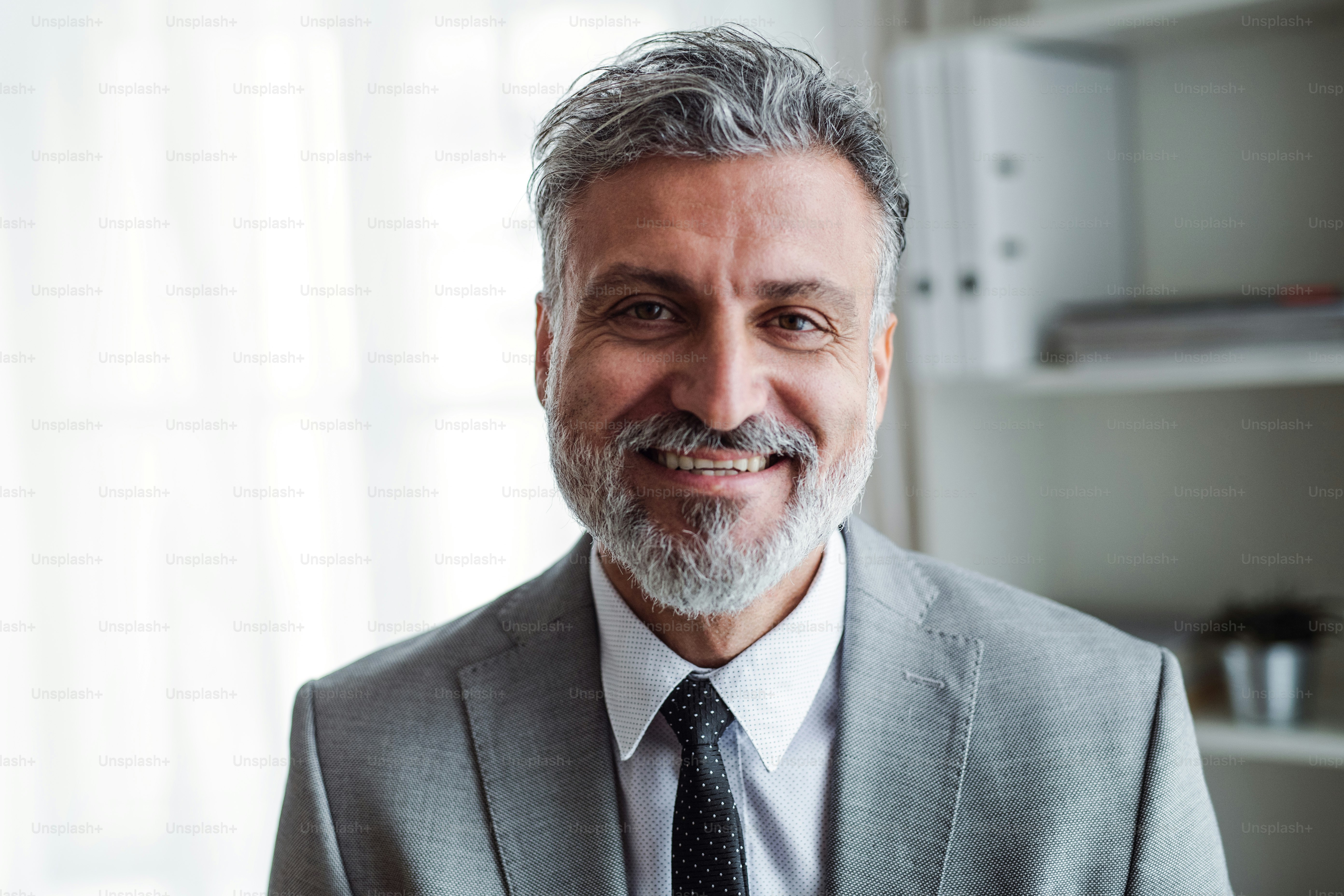 A portrait of cheerful mature businessman standing in an office. photo ...
