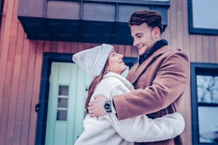 Warm grey hat. Dark-haired girlfriend wearing grey hat looking at her handsome man