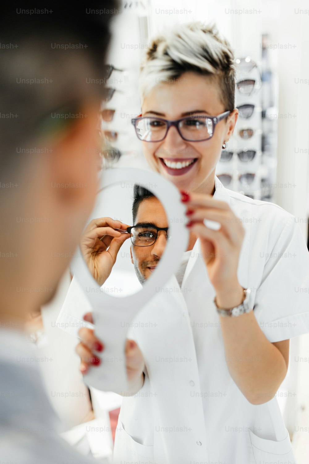 Un optométriste attrayant aide le client à choisir les bonnes lunettes.
