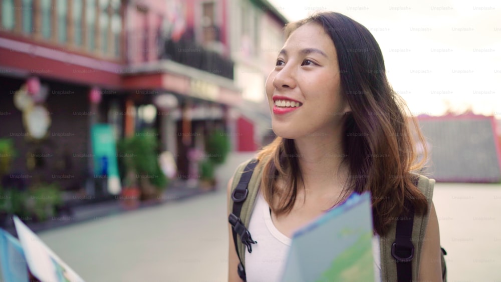 Cheerful beautiful young Asian backpacker woman direction and looking on location map while traveling at Chinatown in Beijing, China. Lifestyle backpack tourist travel holiday concept.
