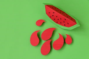 Paper watermelon slice with splashes on green pastel background. Creative idea. Art food concept.