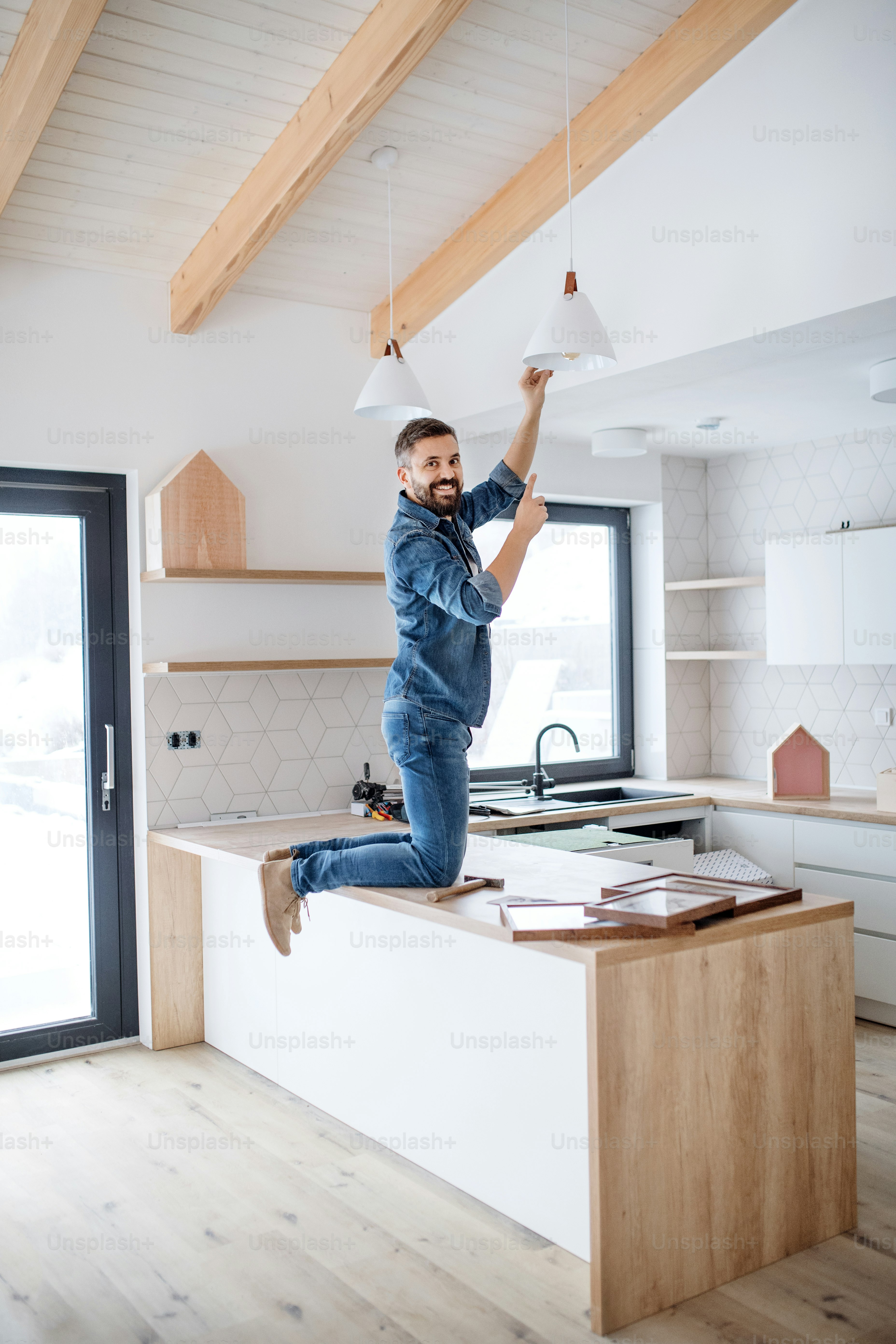 A cheerful senior man helping his mature son with furnishing new house ...