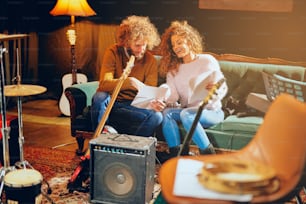 Woman and man with curly hair looking at notes and preparing for the gig. Home studio interior.