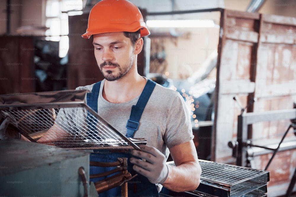 Porträt eines jungen Arbeiters mit Schutzhelm in einer großen Müllrecyclingfabrik. Der Ingenieur überwacht die Arbeit von Maschinen und anderen Geräten.