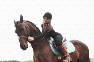 Young pretty girl - riding a horse, equestrian sport in spring time.