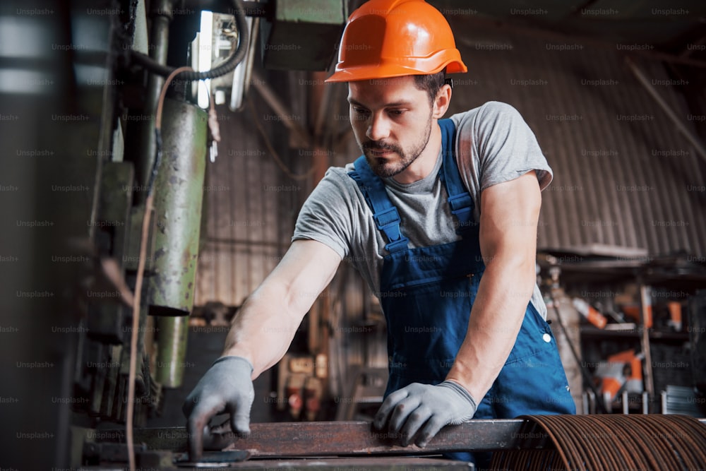 Portrait d’un jeune ouvrier portant un casque de protection dans une grande usine de recyclage de déchets. L’ingénieur surveille le travail des machines et autres équipements.