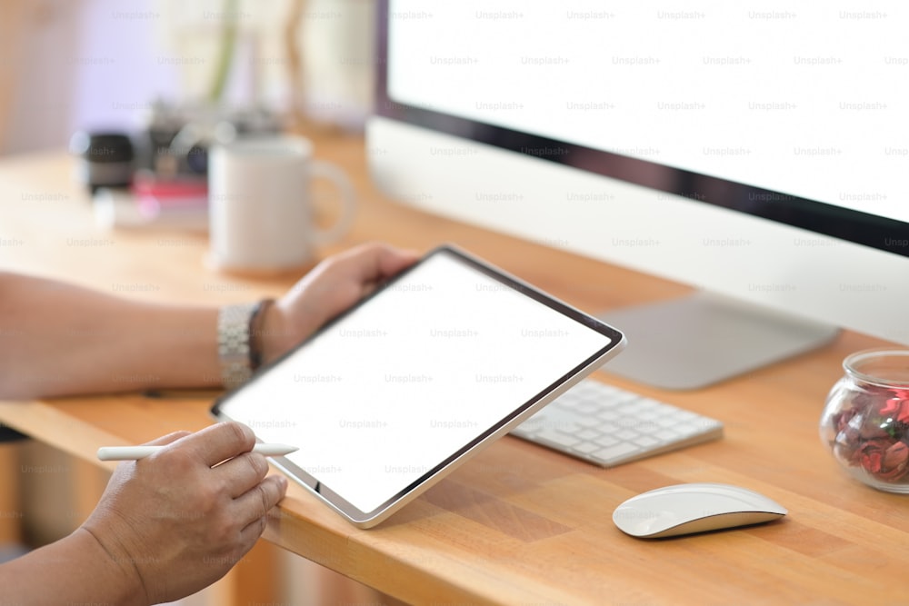 Cropped shot of male hand drawing at portable tablet computer at wooden table studio desk