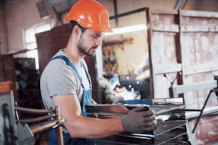 Portrait of a young worker in a hard hat at a large waste recycling factory. The engineer monitors the work of machines and other equipment.