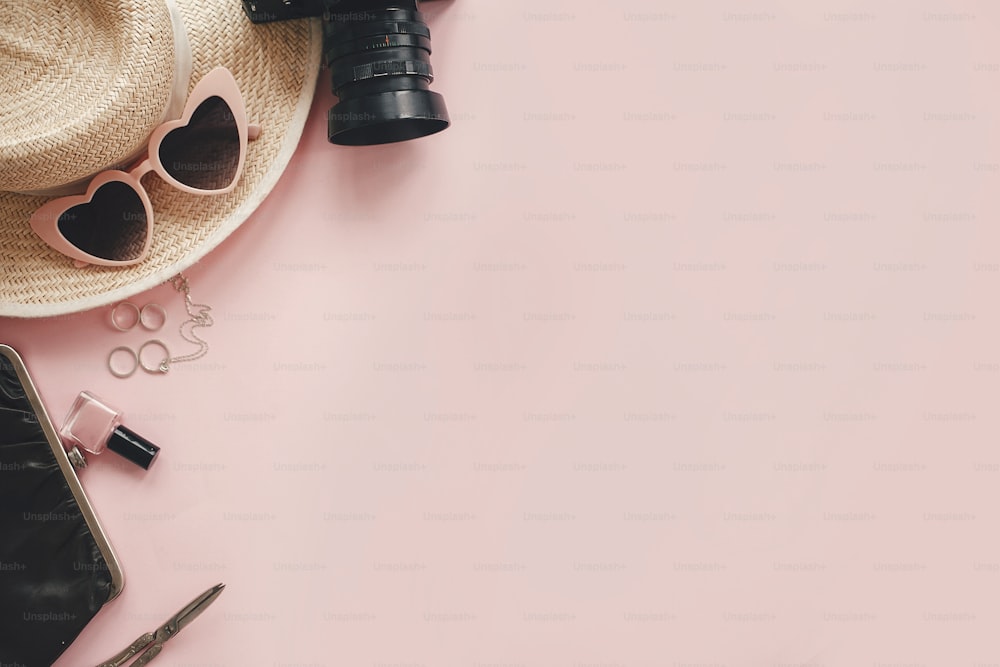 Stilvolle Fotokamera, Sonnenbrille, Schmuck, Strohhut, Tasche, Kosmetik auf rosa Papier flach lag mit Platz für Text. Hallo Sommer.  Internationaler Frauentag.