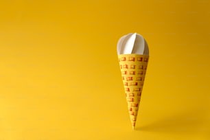 Cone de sorvete de baunilha de papel no fundo amarelo. Espaço de cópia. Conceito de alimento criativo ou artístico