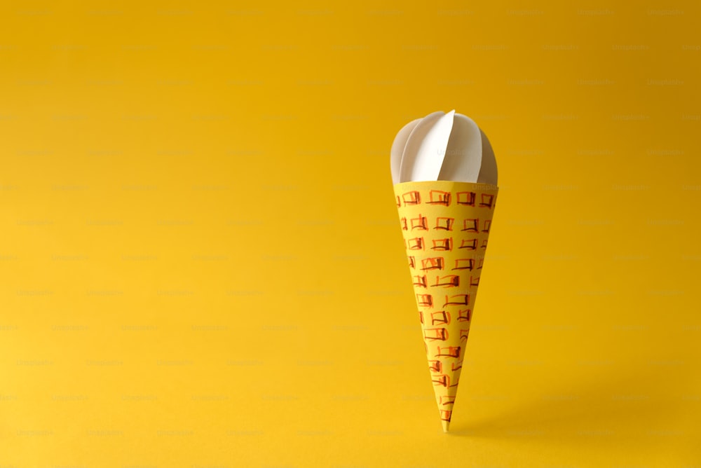 Paper vanilla ice-cream cone on yellow background. Copy space. Creative or art food concept