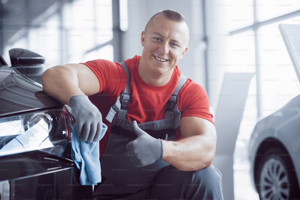 The man holds the microfiber in hand and polishes the car. The new machine is being prepared for sale.