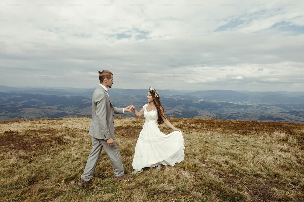 happy gorgeous bride and groom walking  in sun light, boho wedding couple, luxury ceremony at mountains with amazing view