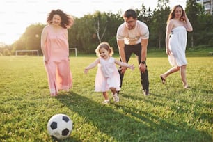 Rilassati con tutta la famiglia. Diverse generazioni di genere si sono riunite per una passeggiata nel parco. La nipote e il nonno giocano a calcio.
