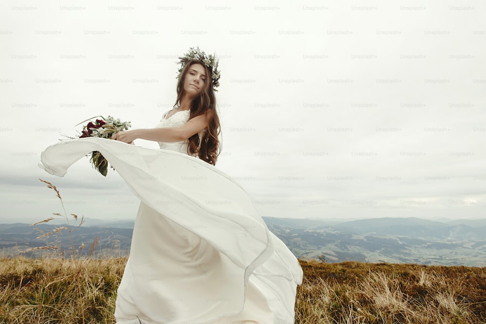 gorgeous bride dancing and having fun holding dress, boho wedding, luxury ceremony at mountains