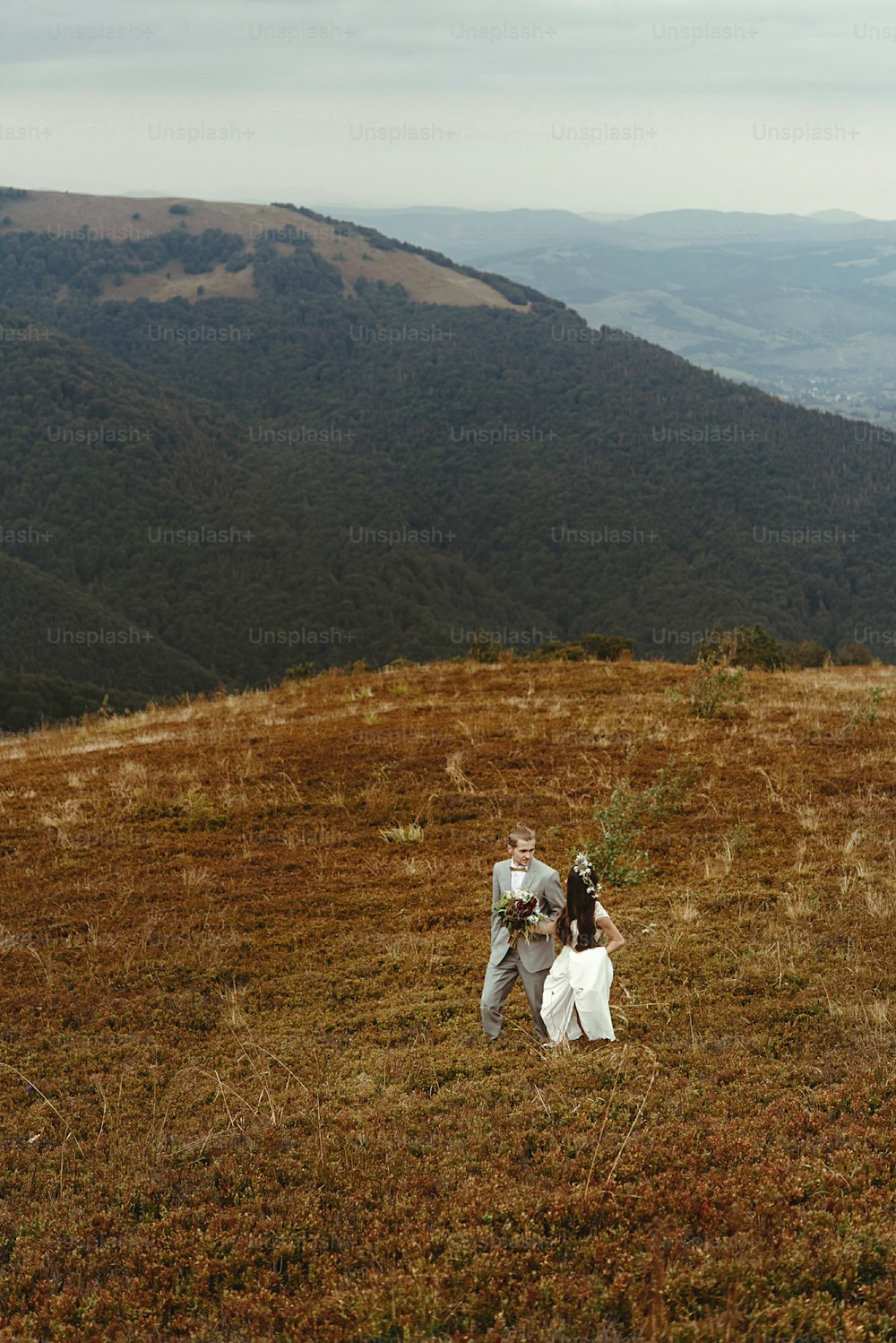 gorgeous bride and stylish groom walking,  boho wedding couple, luxury ceremony at mountains with amazing view, space for text