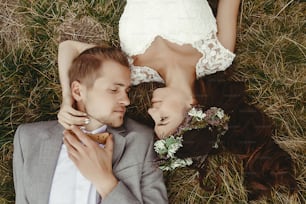 gorgeous bride and stylish groom lying on top, close up, boho wedding couple, luxury ceremony at mountains