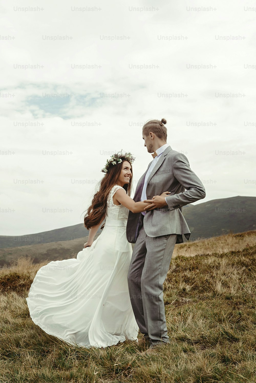 happy gorgeous bride and groom dancing on top of a mountain, luxury ceremony , space for text, boho wedding couple