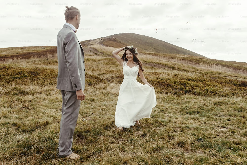 novia hermosa feliz corriendo al novio y divirtiéndose, ceremonia de lujo en las montañas con vista increíble, espacio para texto, pareja de bodas boho