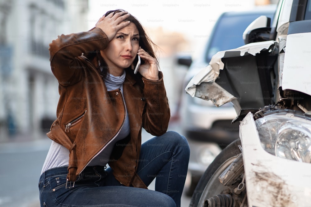 Frustrated woman calling for road assistance after the car accident.