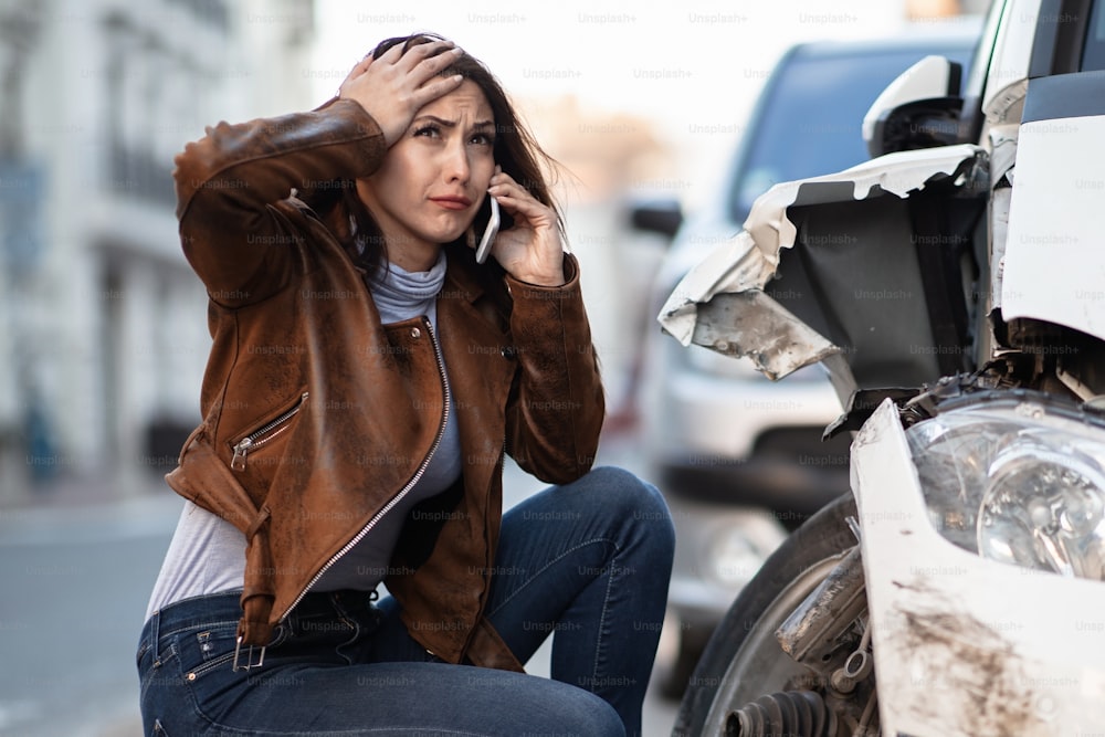 Mujer frustrada que pide asistencia en carretera tras el accidente de coche.
