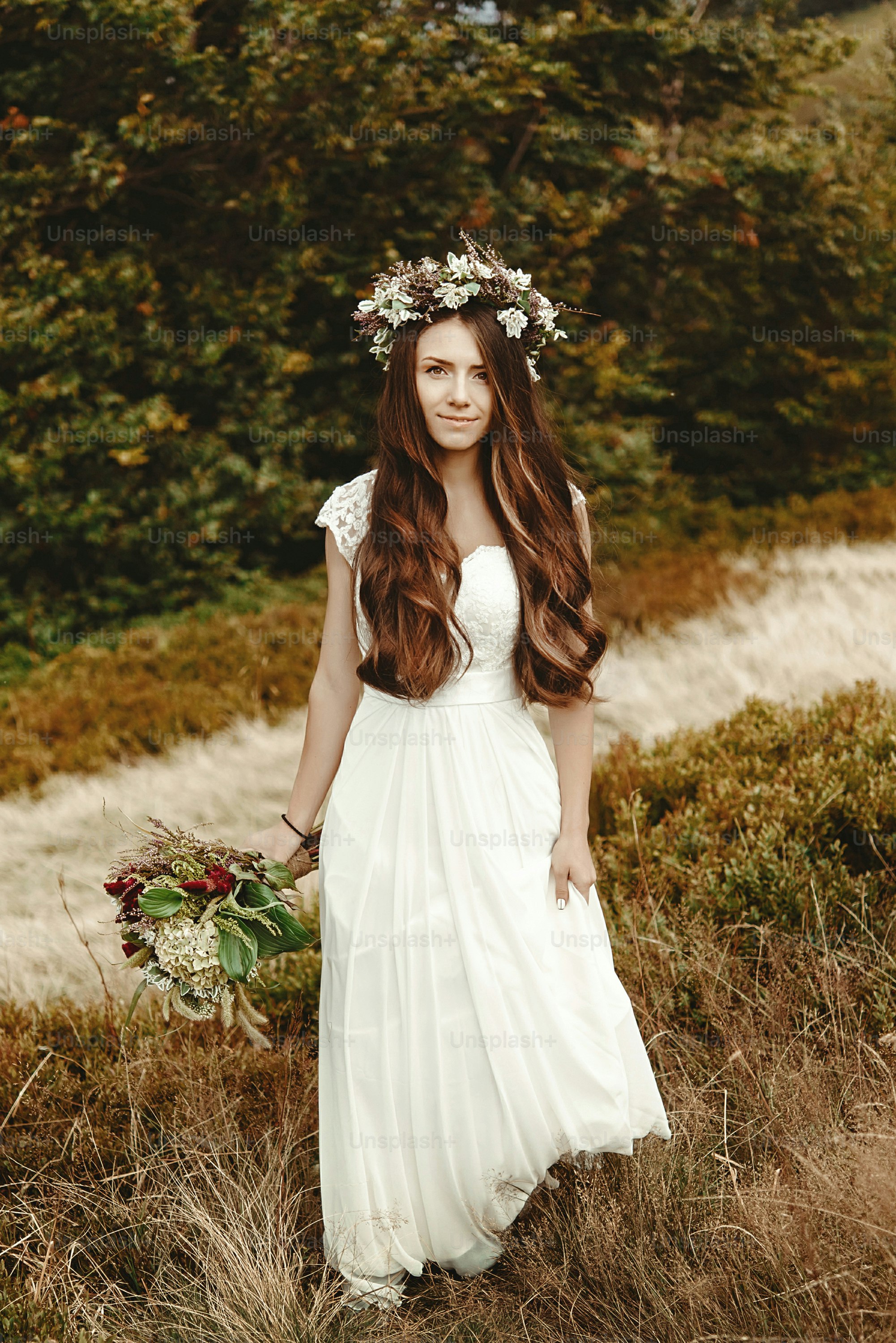 stylish bride posing with bouquet on background of forest, luxury gorgeous boho wedding at mountains