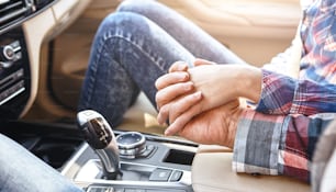 Young man change speed, shifting gears holding hand on gearbox together with his girlfriend's hand. Side view