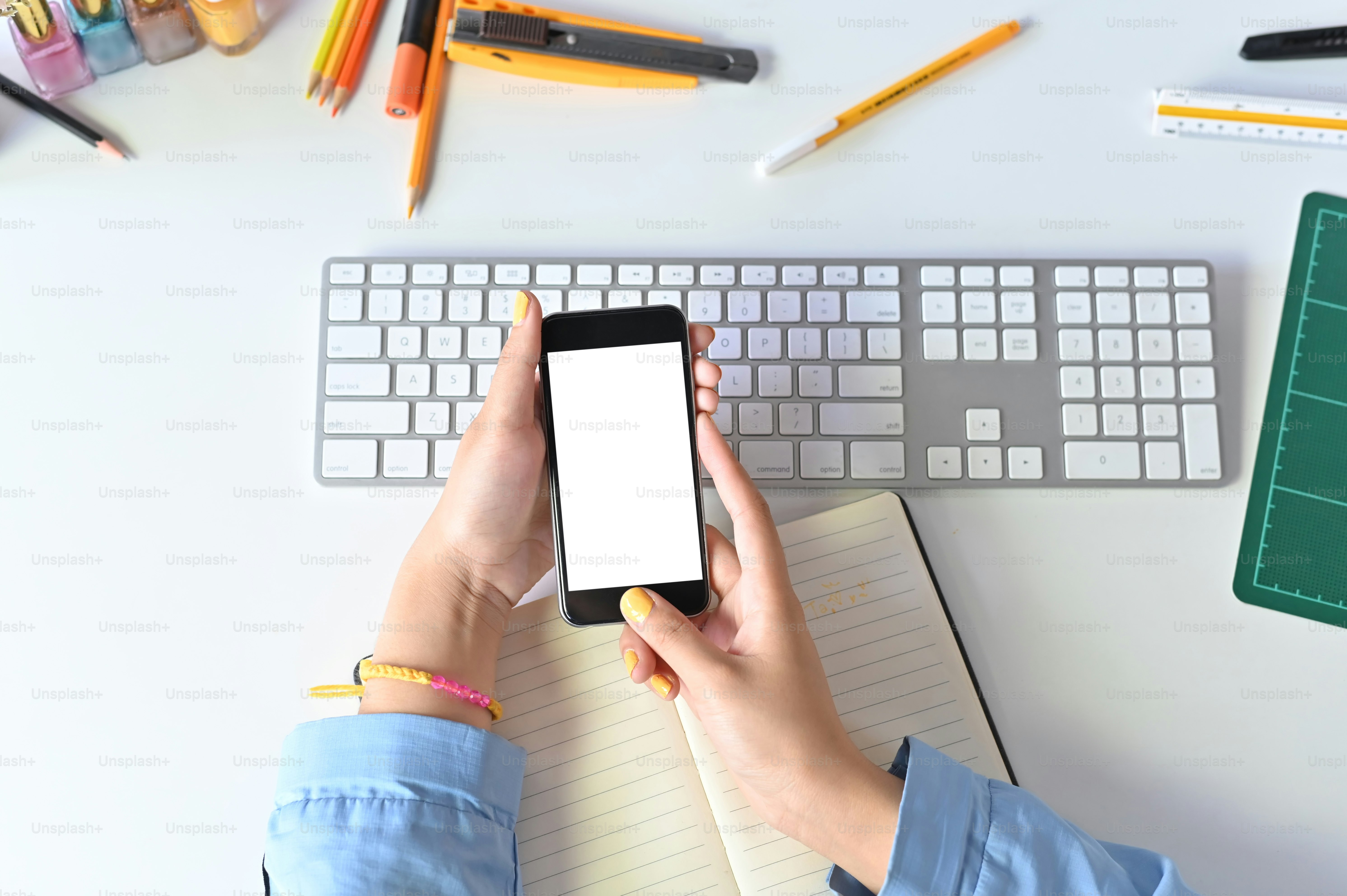 Maket smartphone di tangan wanita menggunakan ruang kerja kantor.