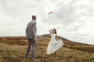 happy gorgeous bride running to groom and having fun, luxury ceremony at mountains with amazing view, space for text, boho wedding couple