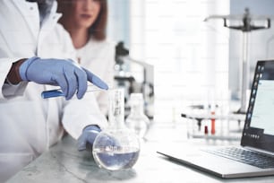 Laborlaboratorien führen Experimente in einem chemischen Labor in transparenten Kolben durch. Ausgabeformeln.