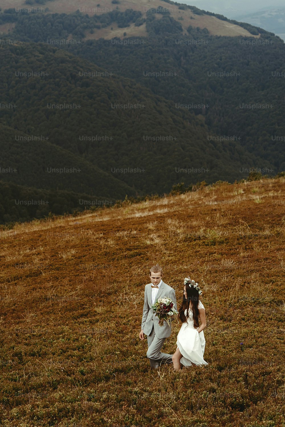 gorgeous bride and stylish groom walking,  boho wedding couple, luxury ceremony at mountains with amazing view, space for text