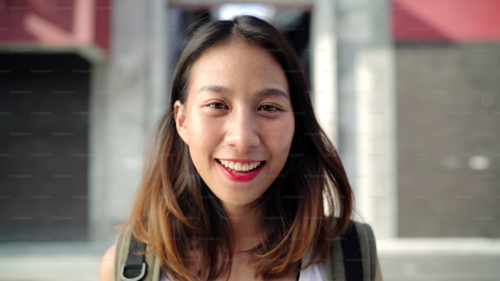 Cheerful beautiful young Asian backpacker woman feeling happy smiling to camera while traveling at Chinatown in Beijing, China. Lifestyle backpack tourist travel holiday concept.