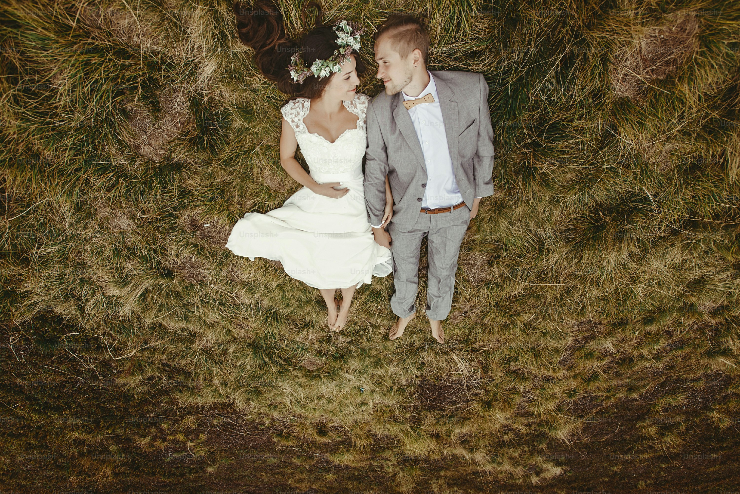 gorgeous bride and stylish groom lying on top, boho wedding couple, luxury ceremony at mountains