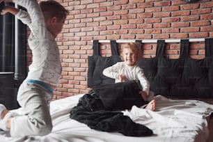 Bambini cattivi Il bambino e la bambina hanno inscenato una lotta con i cuscini sul letto in camera da letto. A loro piace quel tipo di gioco.