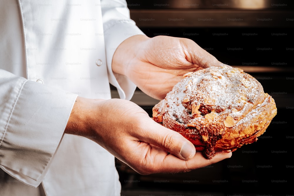 Bun with nuts. Yummy sweet bun with nuts and chocolate just from the oven in hands of baker