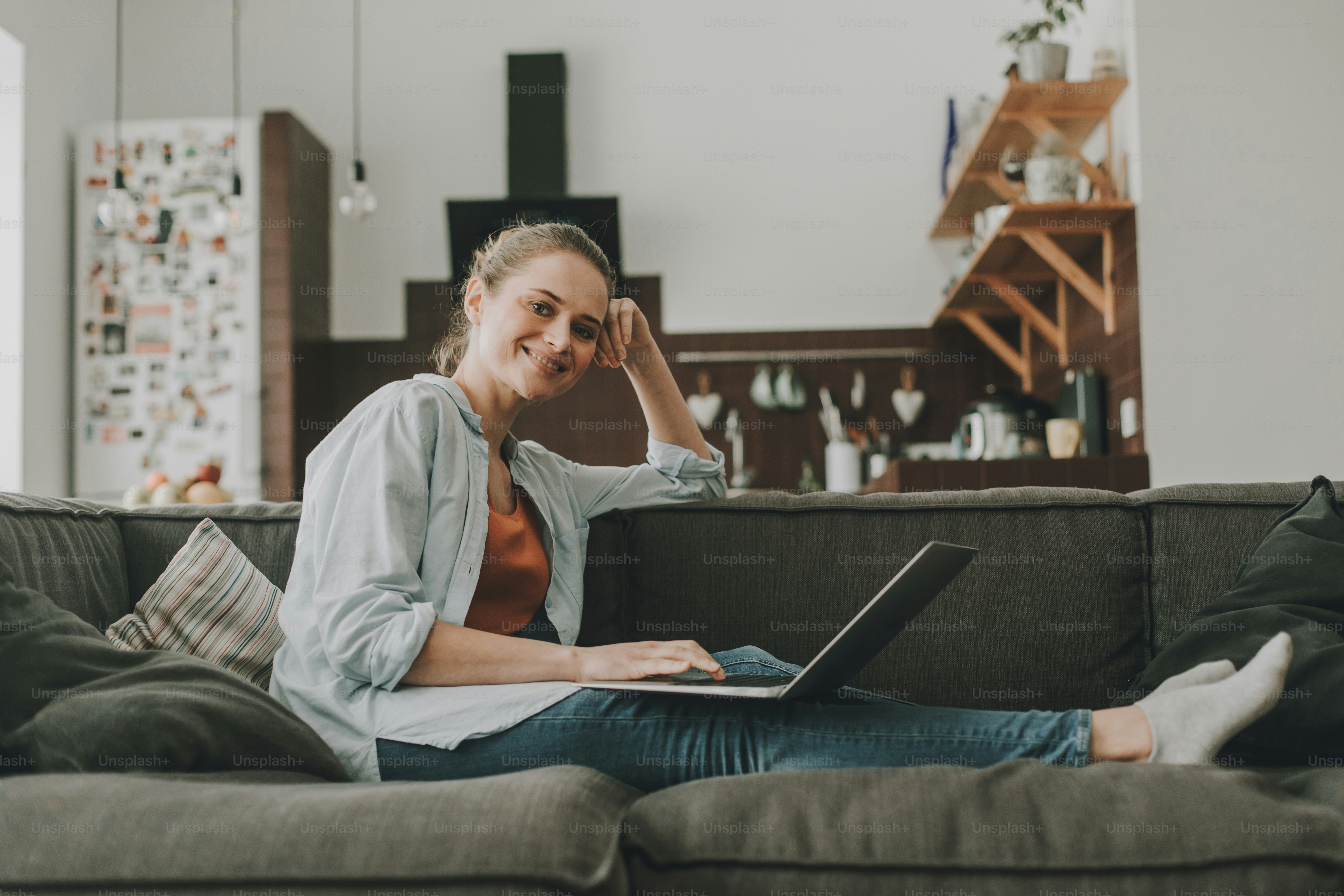 Kommunikation ist sehr wichtig. Porträt einer entspannt lächelnden Frau, die zu Hause auf der Couch sitzt und auf dem Laptop plaudert. Blick auf die Kamera
