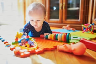 床のおもちゃで遊んでいる女の赤ちゃん。家で幸せな健康な小さな子供