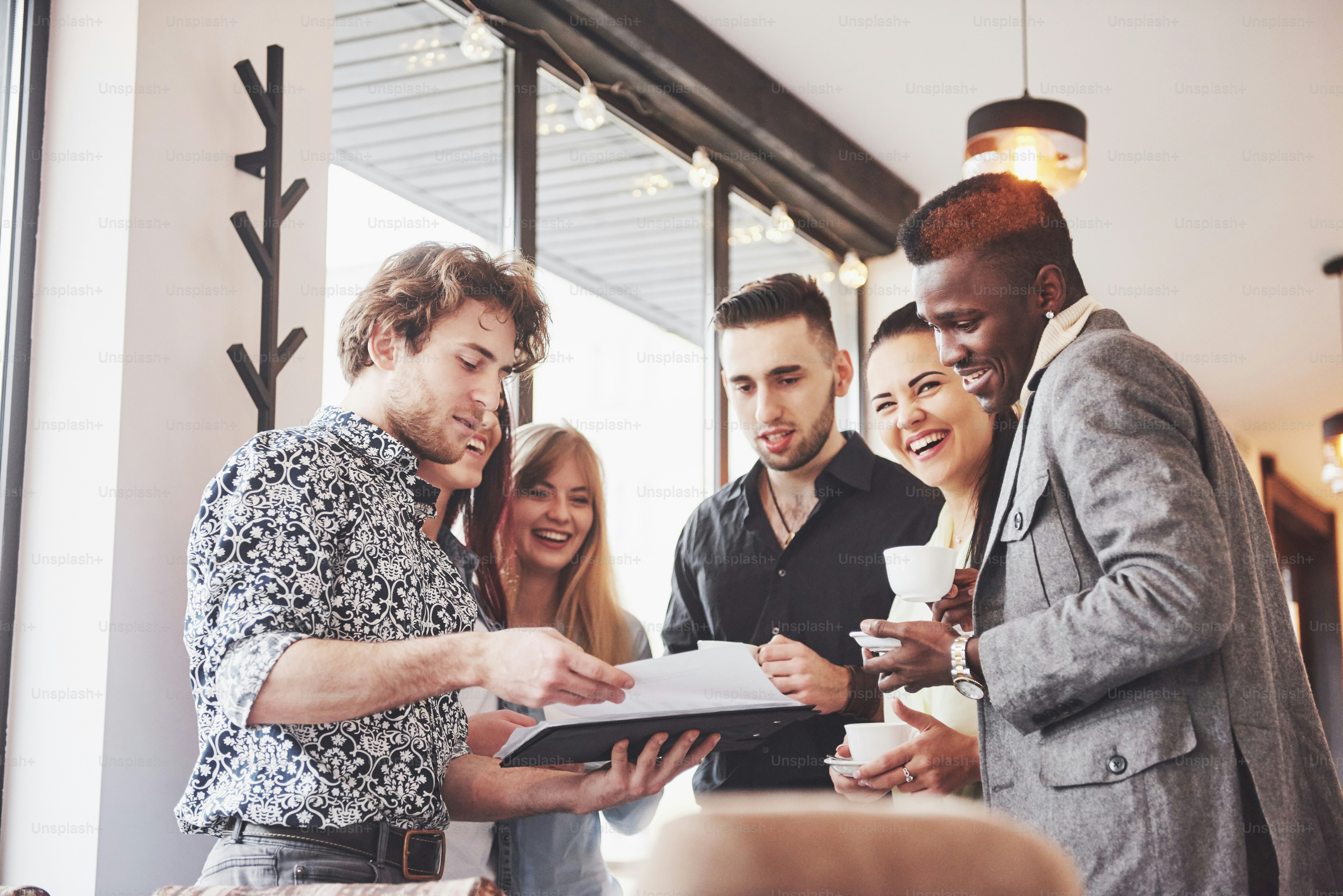 Successful young business people are talking and smiling during the coffee break in office.