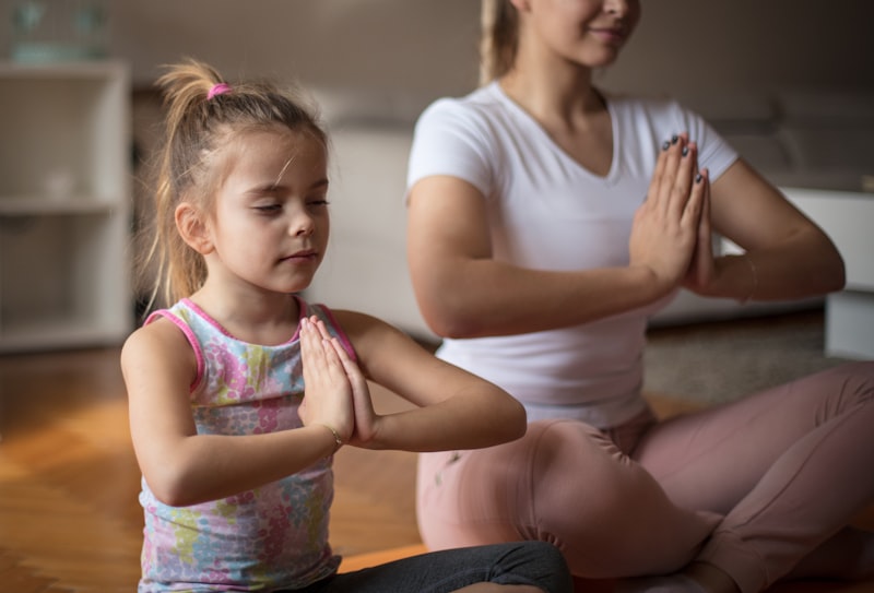 Mutter und Tochter in Namaste-Pose beim Kinderyoga — gemeinsam zur Ruhe finden